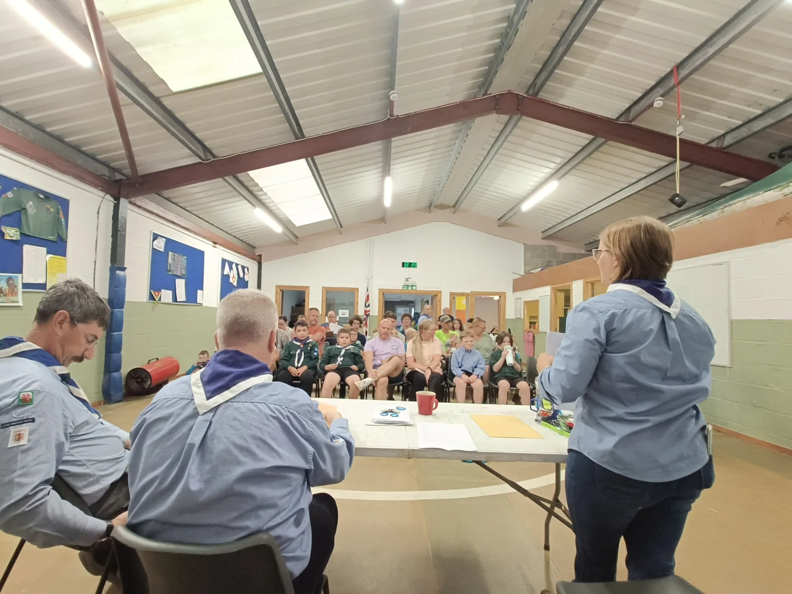 People gathered around a table inside the scout hut
